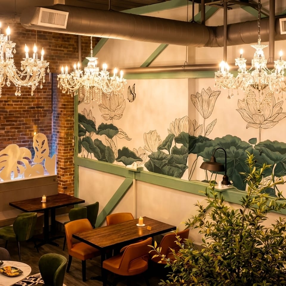 Restaurant interior with crystal chandeliers, brick walls, and a mural of lotus flowers and leaves.